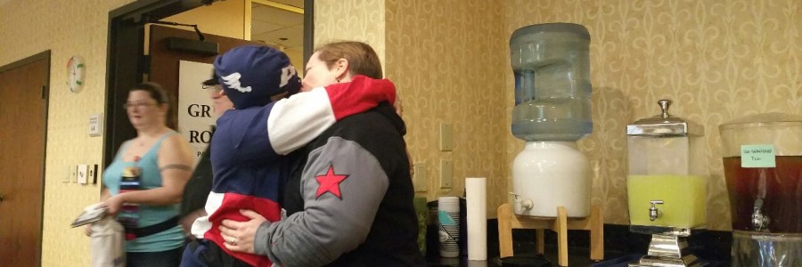 Two women, one in a Captain America hoodie, one in a Winter Soldier hoodie, kissing.